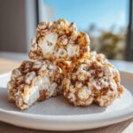 A stack of three gooey, caramel-colored avalanche cookies made with popcorn and white chocolate.