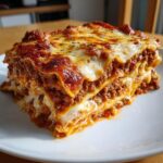 A thick, multi-layered slice of homemade lasagna with rich meat sauce and melted cheese topping.