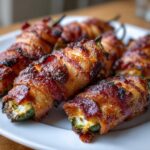 Close-up of several perfectly cooked Bacon-Wrapped Jalapeño Poppers with crispy bacon and visible cream cheese filling.