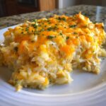 A scoop of cheesy chicken and rice casserole topped with melted cheddar cheese and parsley.