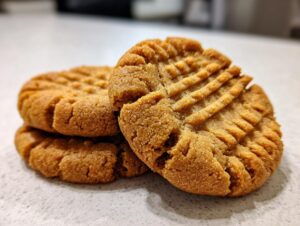 A close-up stack of three golden brown peanut butter cookies showing the classic crisscross fork marks on top.