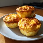 Three golden brown cottage cheese egg cups starbucks style muffins stacked on a light blue plate.