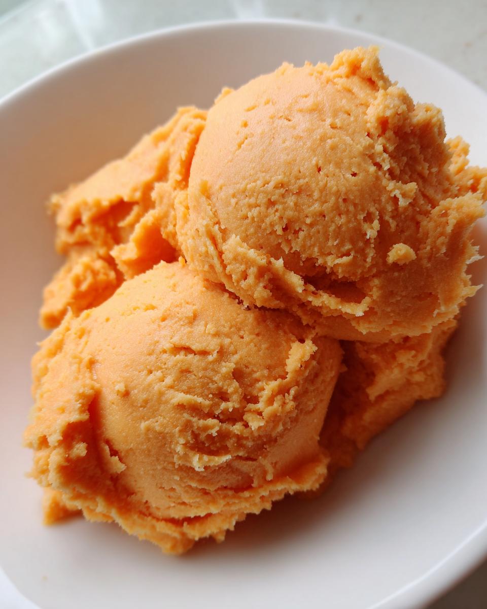 Close-up of three scoops of creamy mashed sweet potatoes in a white bowl.