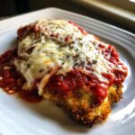 Close-up of a golden-brown breaded cutlet topped with rich marinara sauce and melted mozzarella cheese for Easy Chicken Parmesan.