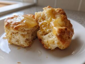 Close-up of fluffy sweet potato biscuits split open and drizzled generously with melted honey or glaze.