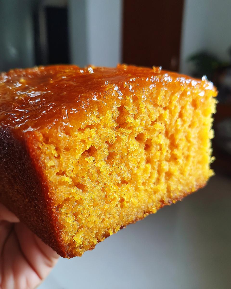 A close-up, macro shot showing the moist, orange crumb and shiny glaze of a sweet potato cornbread bite.