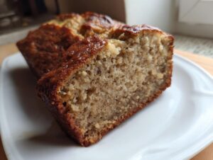 Close-up of a moist slice of greek yogurt banana bread showing its soft crumb texture on a white plate.