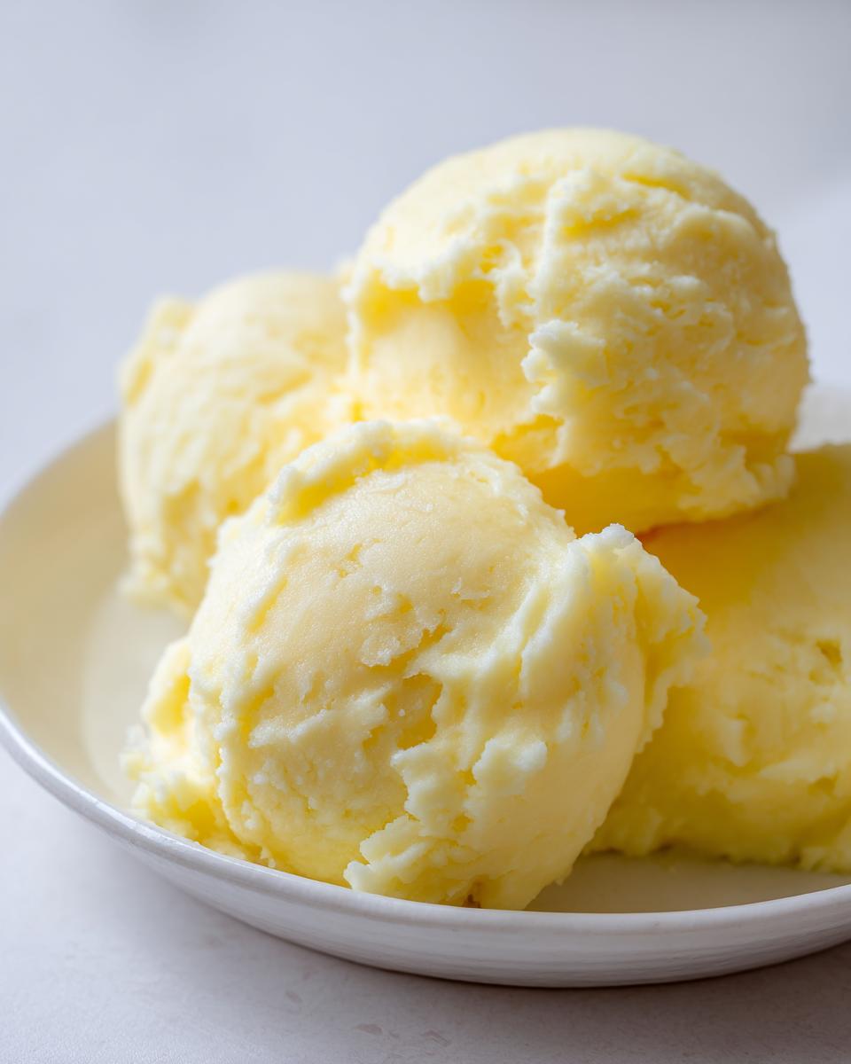 Four scoops of rich, yellow creamy mashed potatoes served in a shallow white bowl.