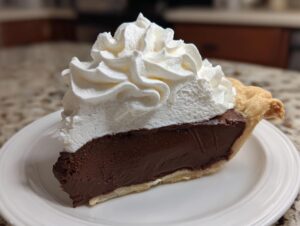 A perfect slice of chocolate cream pie featuring a thick, dark chocolate filling and a generous swirl of whipped cream topping.
