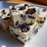 Close-up of creamy white squares of 3-Ingredient oreo fudge studded with crushed chocolate sandwich cookies.