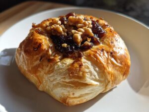 A golden, flaky puff pastry parcel topped with jam and walnuts, representing a quick baked brie appetizer.