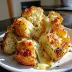 Close-up of warm, pull-apart cheese bread with melted, stretching mozzarella cheese and herbs.