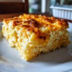 A close-up serving of cheesy potato comfort casserole with a golden, bubbly, and browned cheese topping.