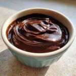 Close-up of incredibly rich and creamy chocolate pudding swirled high in a small, light blue ramekin.