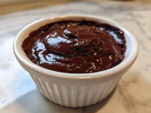 Close-up of rich, dark chocolate pudding served in a white fluted ramekin.