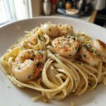 A close-up of creamy seafood pasta featuring linguine tossed in sauce, topped with seared shrimp and scallops.