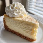 A perfect slice of creamy eggnog cheesecake recipe topped with whipped cream and nutmeg.
