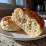 Close-up showing the airy, open crumb structure of a homemade English muffin cut in half.