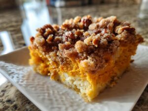 A close-up of a slice of fluffy sweet potato souffle topped with a crunchy pecan streusel.