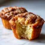 A close-up of a french toast muffin with a bite taken out, revealing the soft interior and cinnamon sugar topping.