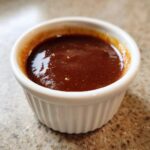 Close-up of thick, glossy homemade teriyaki sauce served in a small white fluted ramekin.
