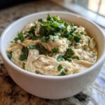 A close-up of a white bowl filled with creamy instant pot white chicken chili, topped with fresh cilantro.
