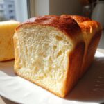 A close-up, cross-section view of a freshly baked japanese milk bread loaf showing its incredibly soft, white crumb.