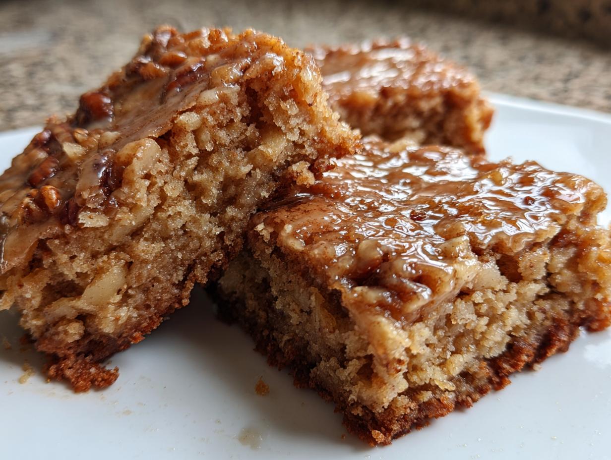 Close-up of moist apple brownies squares topped with a sticky, glossy pecan glaze.