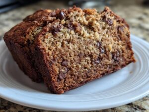 Two moist slices of vegan banana bread studded with chocolate chips served on a white plate.