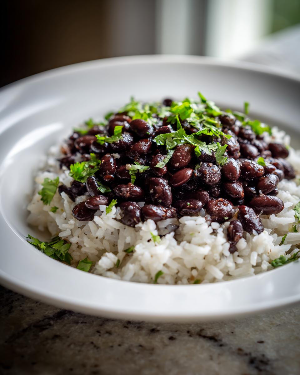 A close-up shot of a white bowl filled with fluffy white rice topped generously with seasoned black beans and fresh cilantro, showcasing the amazing beans and rice.