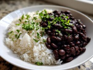 Close-up of a white bowl filled with white rice and seasoned black beans, garnished with fresh parsley, showcasing the beans and rice dish.
