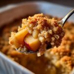 Close-up of a spoonful of amazing apple crumble showing crunchy topping and a tender apple slice.