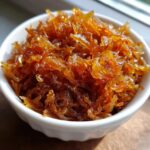 Close-up of richly colored, sweet caramelized onions piled high in a small white bowl.
