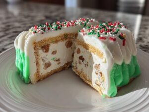 A slice of christmas tree cheesecake cut in half, showing creamy filling with nuts, graham cracker crust, and green and white frosting.