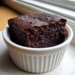 A rich, dark chocolate Cottage Cheese Microwave Brownie served in a small white fluted ramekin.
