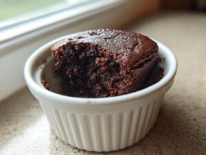 Close-up of a rich, dark chocolate Cottage Cheese Microwave Brownie baked in a white fluted ramekin.