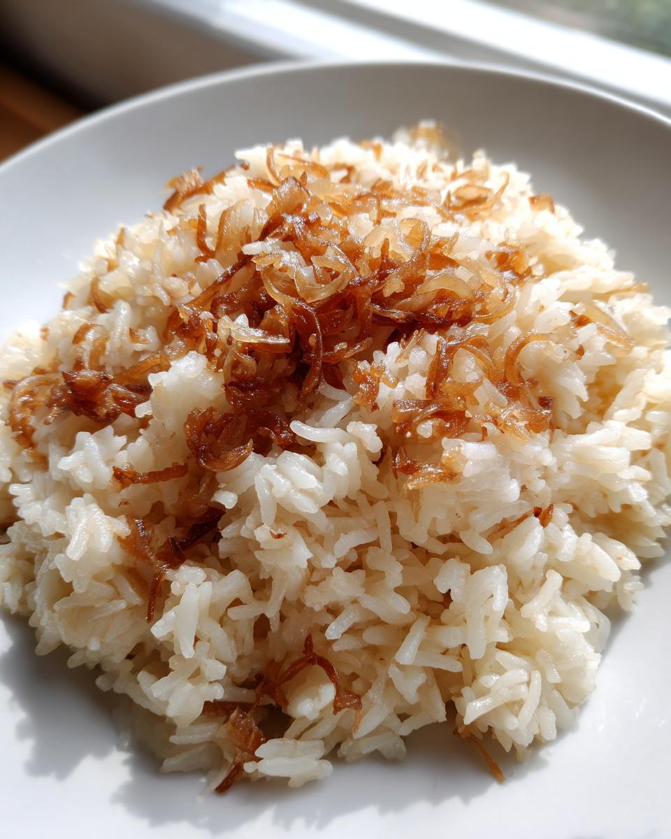 A close-up of fluffy white rice topped generously with crispy caramelized onions, representing french onion butter rice.