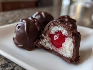 Close-up of homemade chocolate covered cherries, one cut open showing the cherry center and white filling.