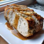 Close-up of three thick slices of juicy instant pot turkey breast, seasoned and covered in savory brown gravy.