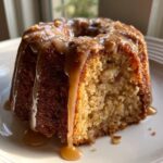 Close-up of a moist slice of apple bundt cake drizzled with thick caramel sauce.