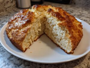 A round loaf of homemade beer bread, cut in half to show the fluffy interior and drizzled with a shiny honey glaze.