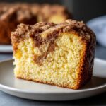 Close-up of a moist slice of coffee cake showing a tender crumb and thick cinnamon streusel layers.