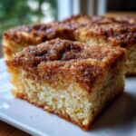 A close-up, tasty shot of a square of snickerdoodle blondies featuring a thick, sugary cinnamon topping.