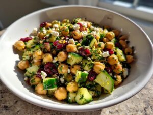 Close-up of an amazing 15-minute bean salad featuring chickpeas, cucumbers, dried cranberries, and feta cheese.