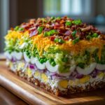 A tall, rectangular block of amazing seven layer salad showing distinct layers of toppings, eggs, and vegetables.