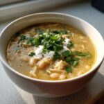 A close-up of a hearty bowl of amazing white chicken chili topped with sour cream and fresh cilantro.