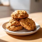 A stack of four golden brown, textured applesauce cookies resting on a small white plate.