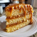 Close-up of a moist slice of caramel cake recipe with thick caramel dripping down the sides.