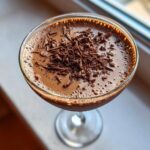 Close-up overhead view of a creamy chocolate martini topped with dark chocolate shavings.