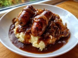 Two browned sausages served over creamy mashed potatoes, smothered in onion gravy for classic bangers and mash.